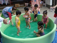 未満児のお友達は小さなプールでおもちゃを使って遊んでいます。
